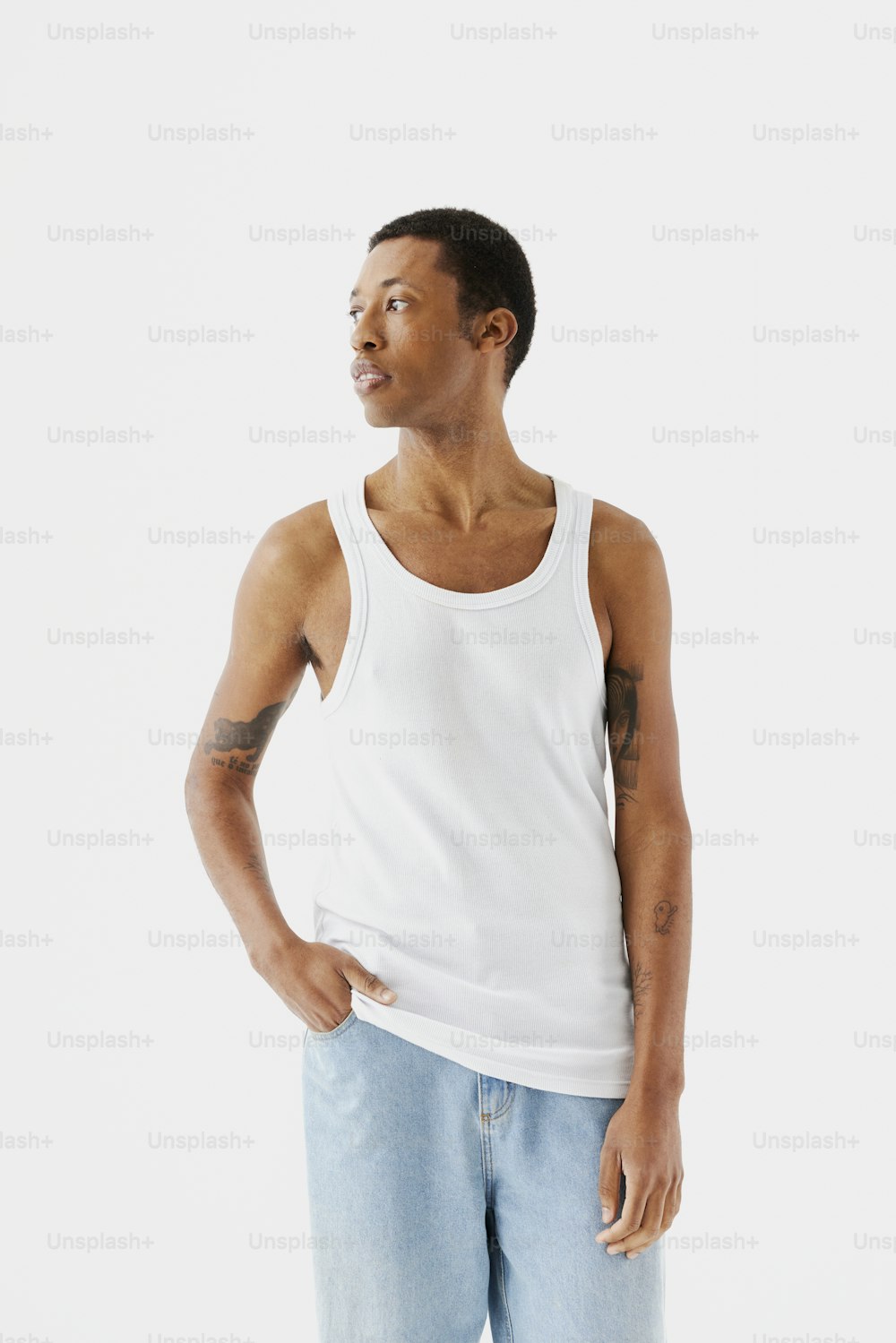 a man in a white tank top is standing with his hands in his pockets
