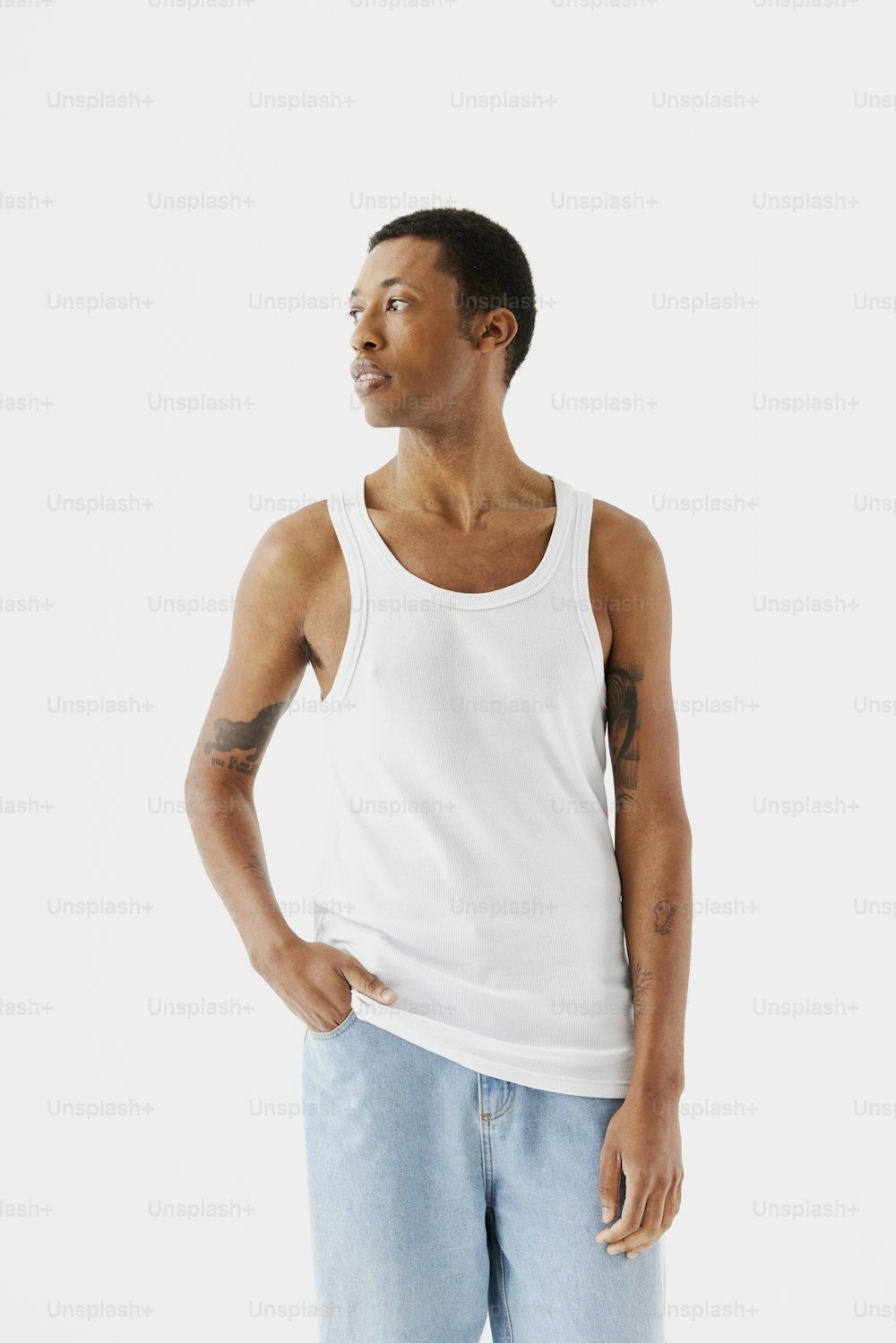 a man in a white tank top is standing with his hands in his pockets