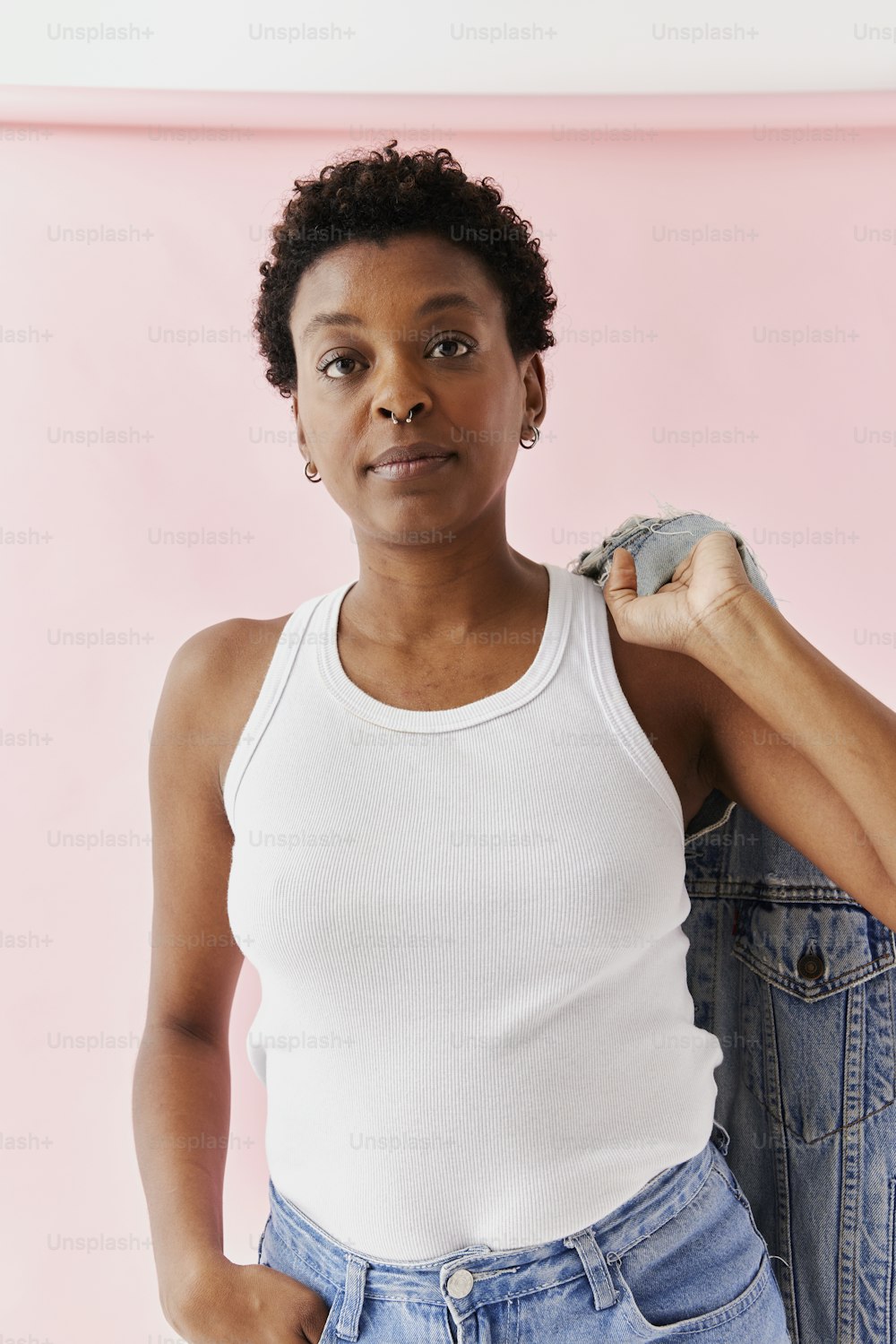 a woman in a white tank top is holding a pair of jeans