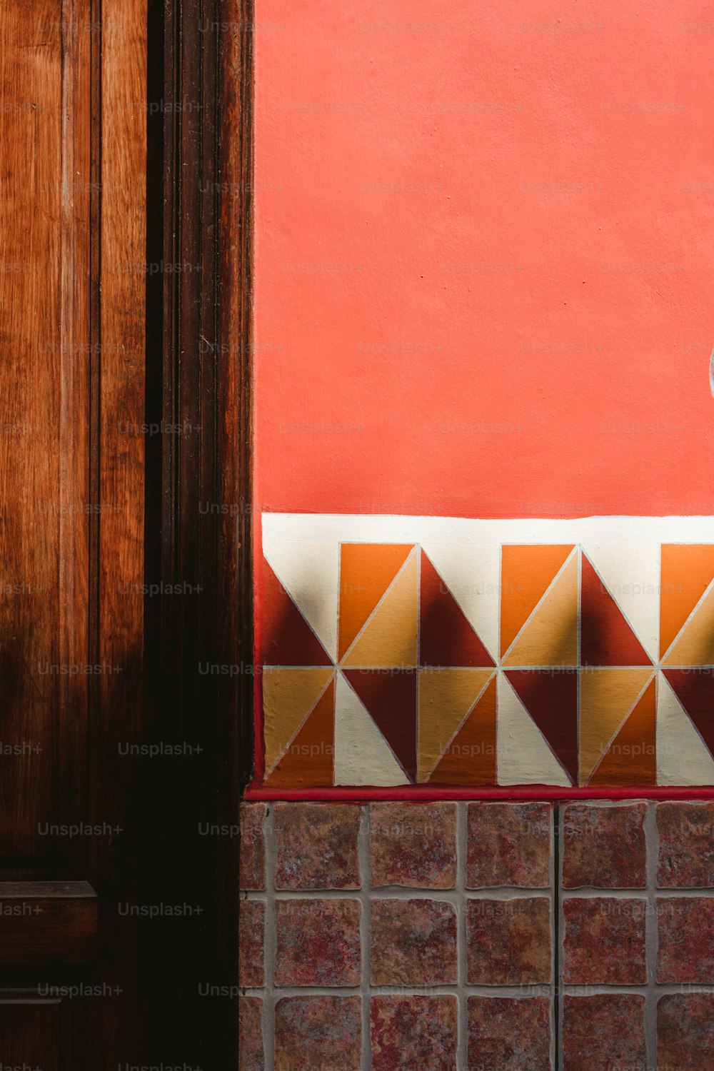 a cat sitting on top of a tiled counter next to a red wall