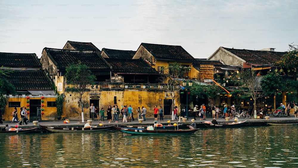 a group of people standing on a pier next to a body of water