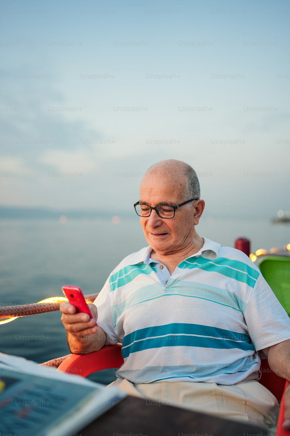 Un uomo seduto su una sedia che guarda un telefono cellulare