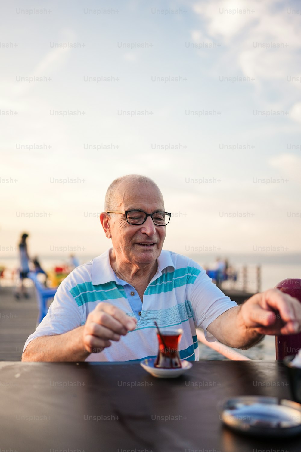 um homem sentado à mesa com uma bebida na mão
