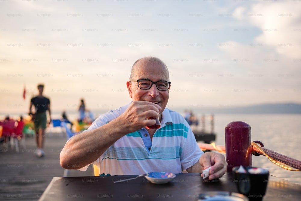 a man sitting at a table eating food by the water