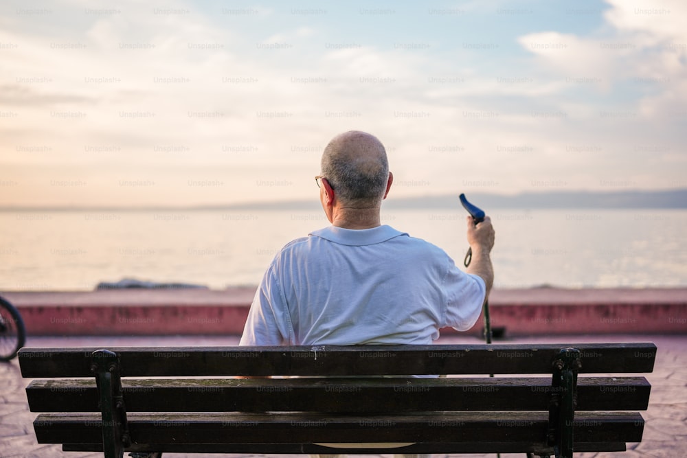 um homem sentado em um banco com um celular na mão