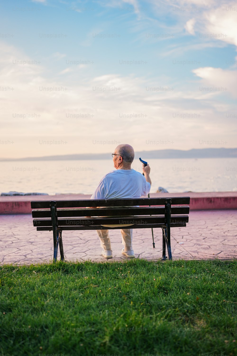 Un hombre sentado encima de un banco junto al océano