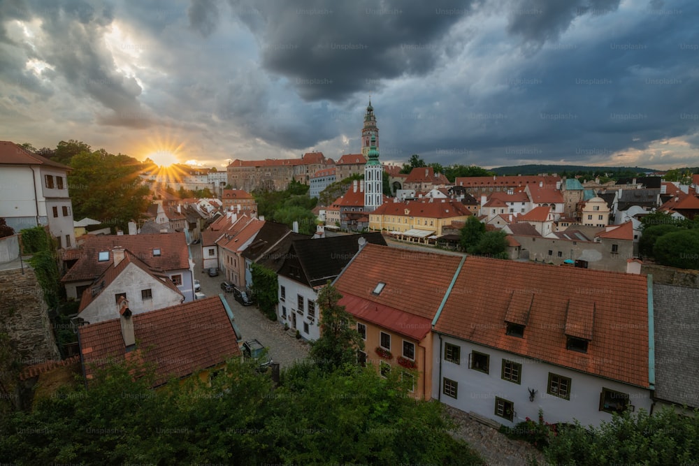 the sun is setting over a city with red roofs