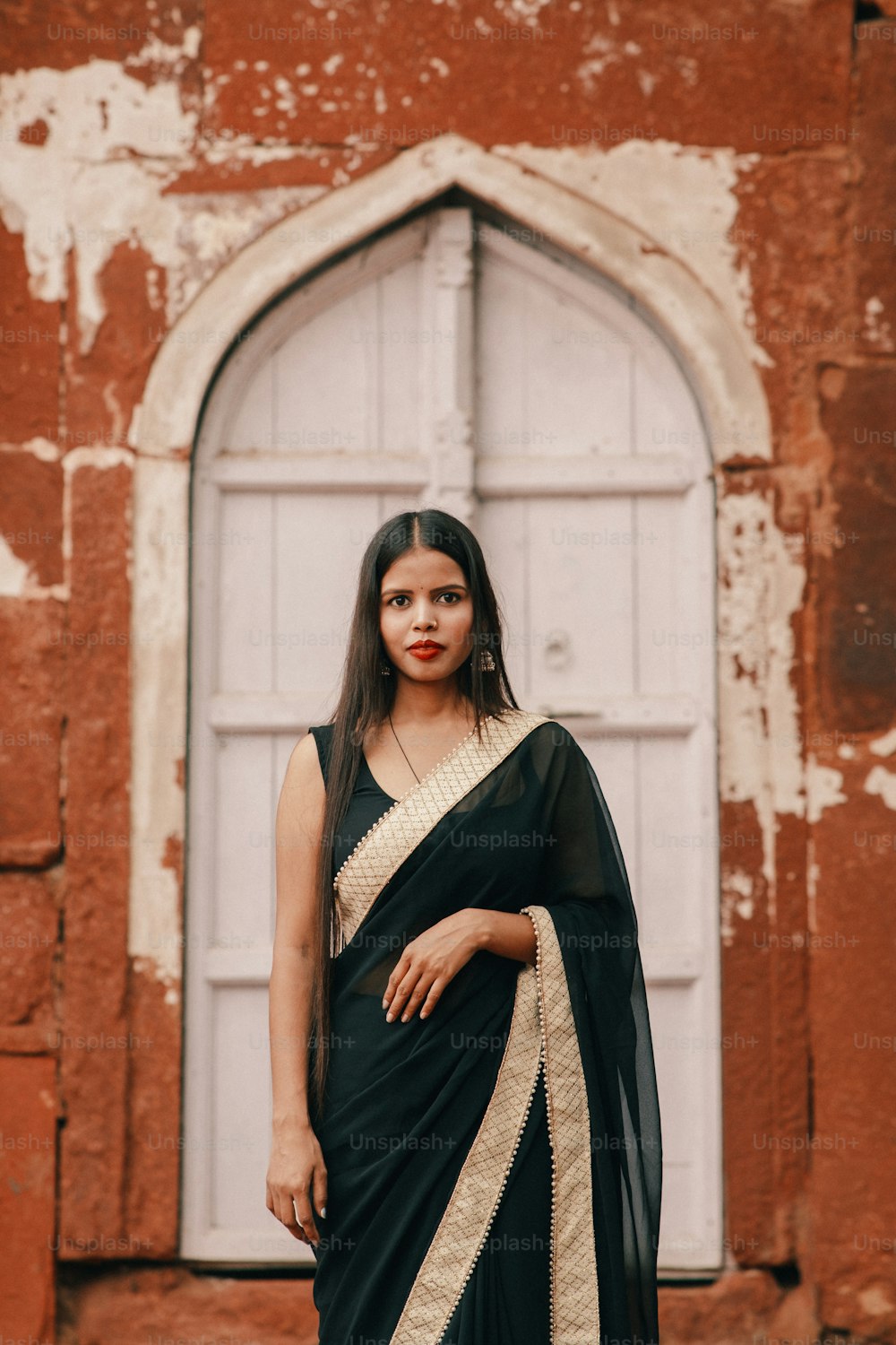 Una mujer con un sari negro parada frente a una puerta
