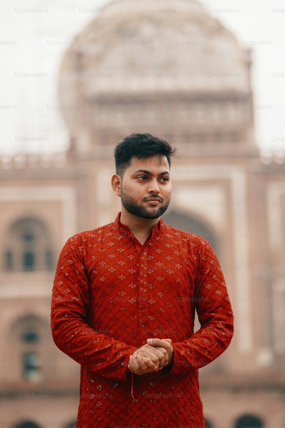 a man in a red shirt standing in front of a building