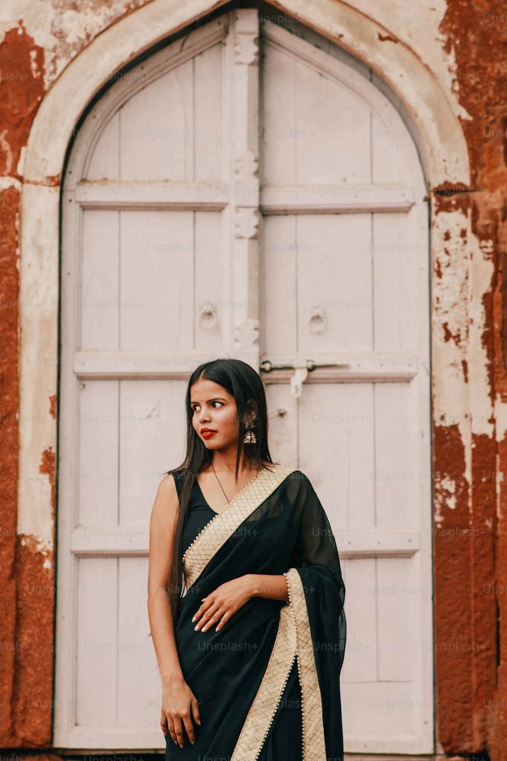 uma mulher em frente a uma porta vestindo um sari preto e branco