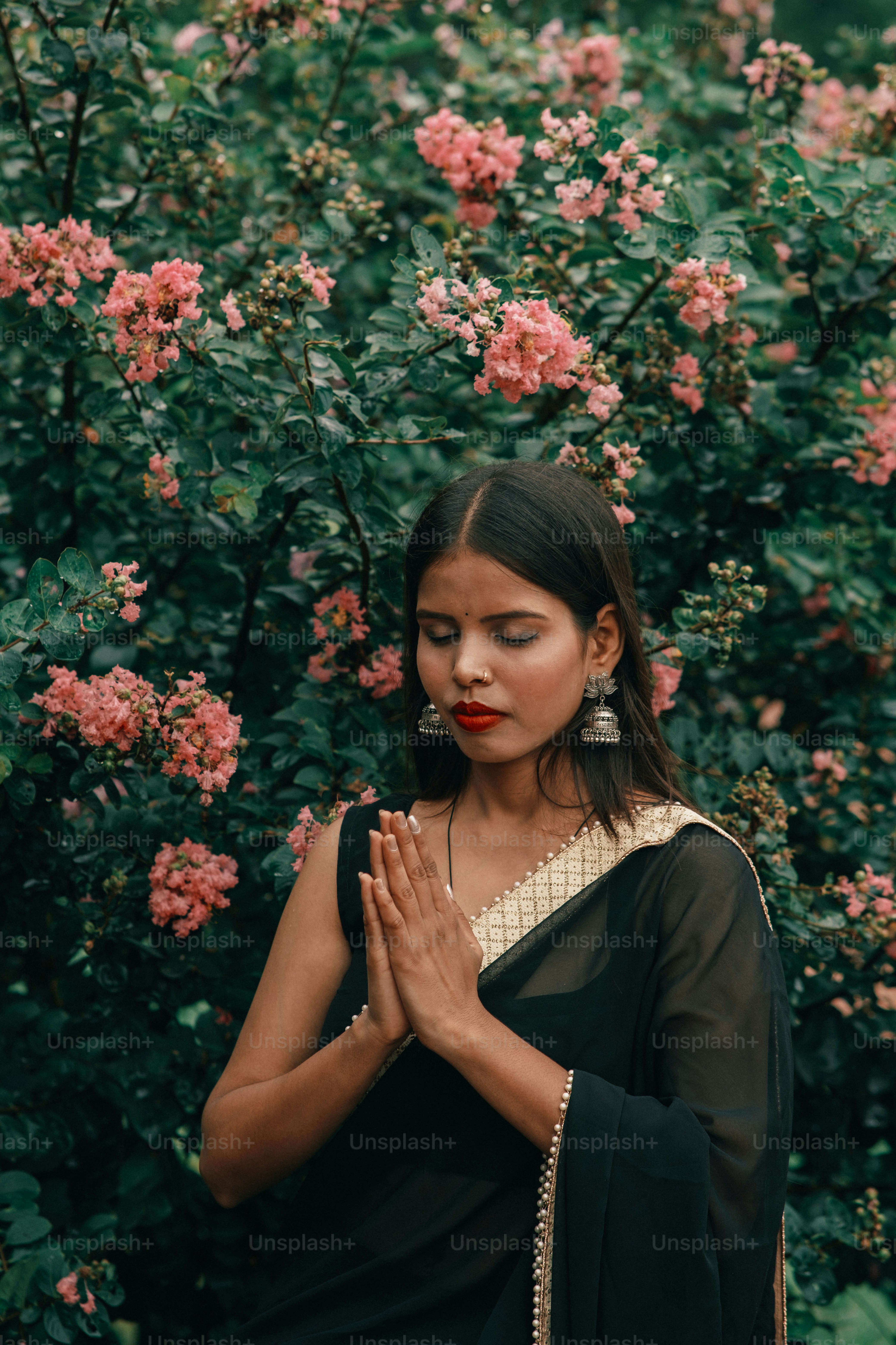 A woman standing in front of a bush with pink flowers photo ...