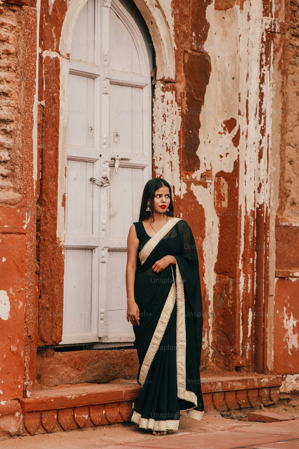 Una mujer en un sari blanco y negro de pie frente a una puerta