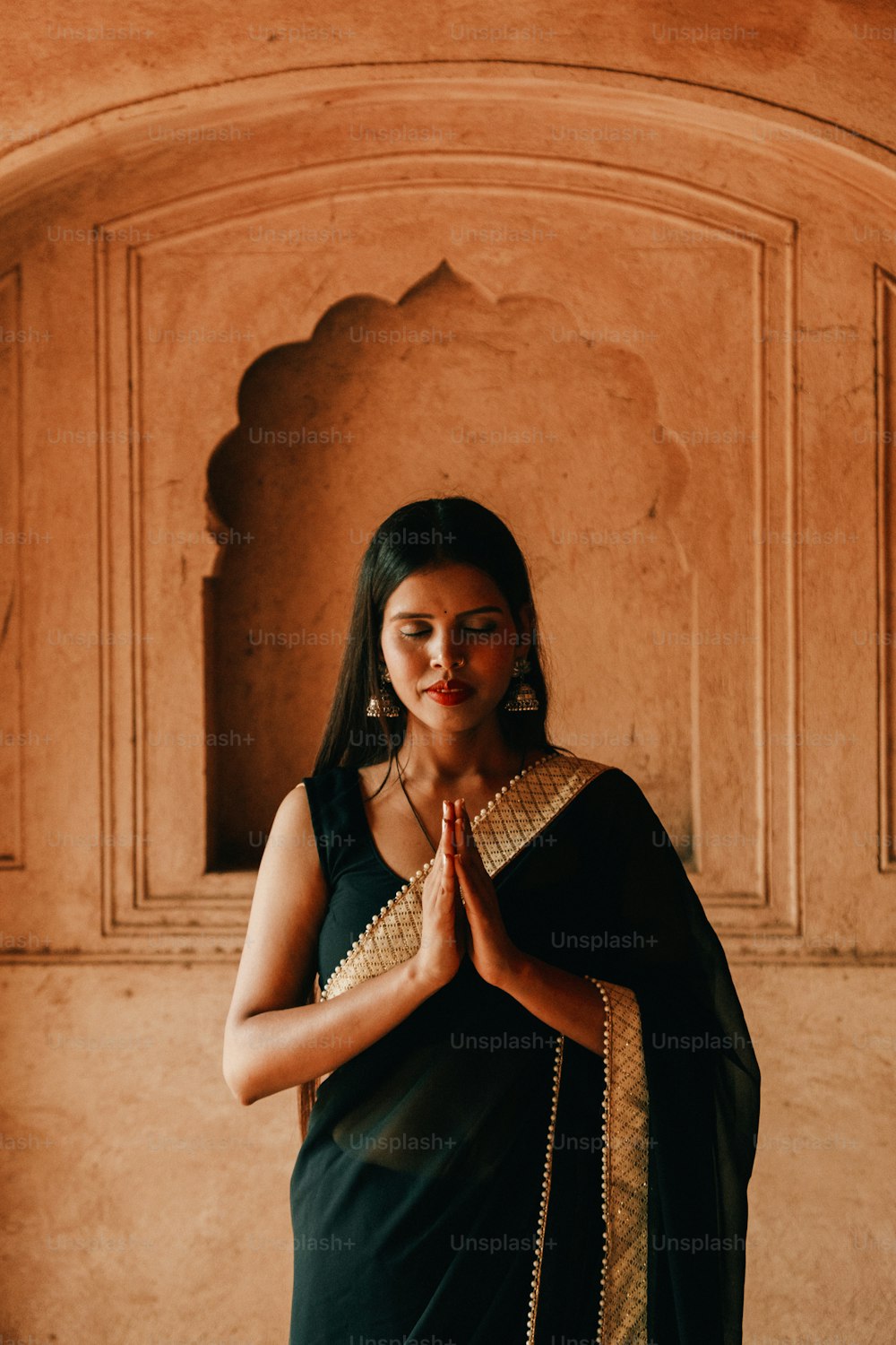Eine Frau in einem schwarzen Sari, die vor einer Wand steht