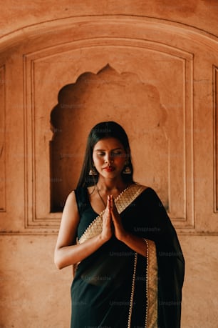 Una mujer con un sari negro parada frente a una pared