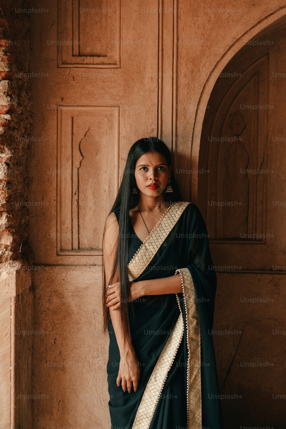 a woman in a black sari standing against a wall