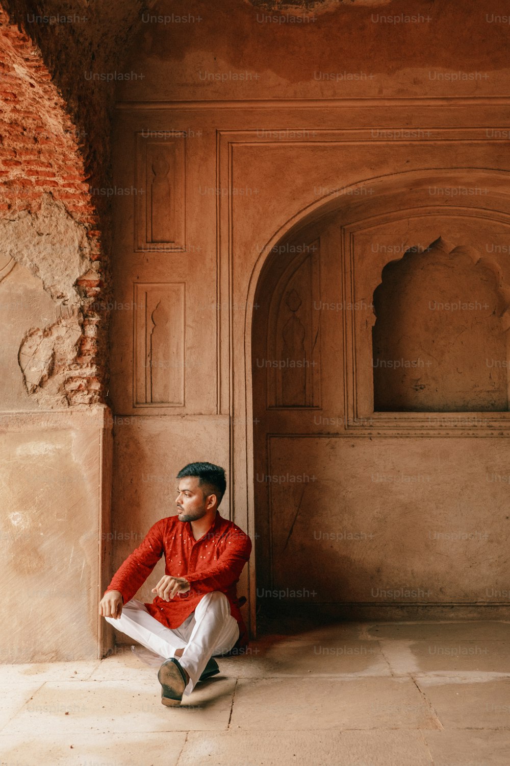 a man in a red shirt and white pants sitting on the floor