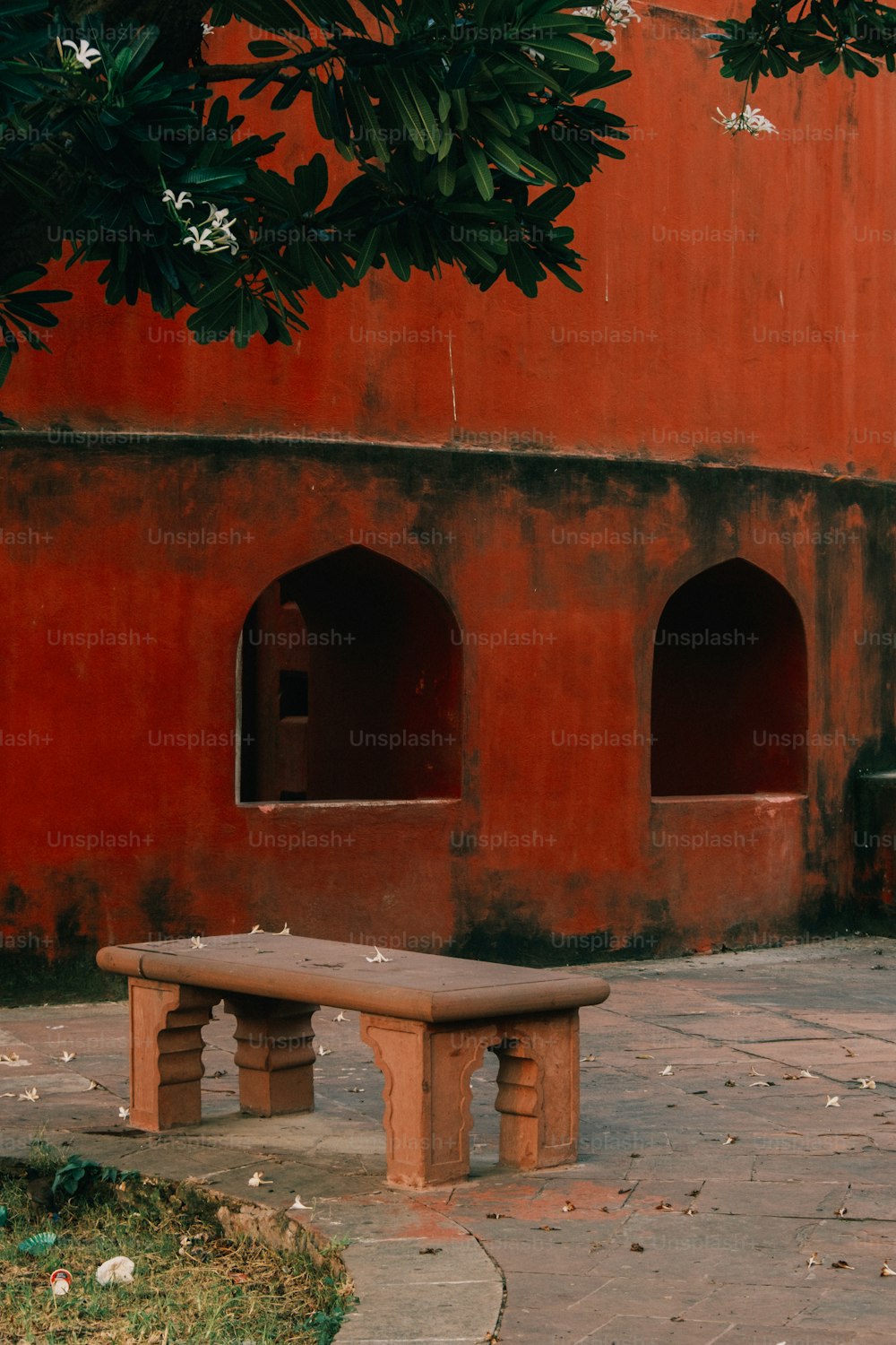 um banco de madeira sentado em frente a um prédio vermelho