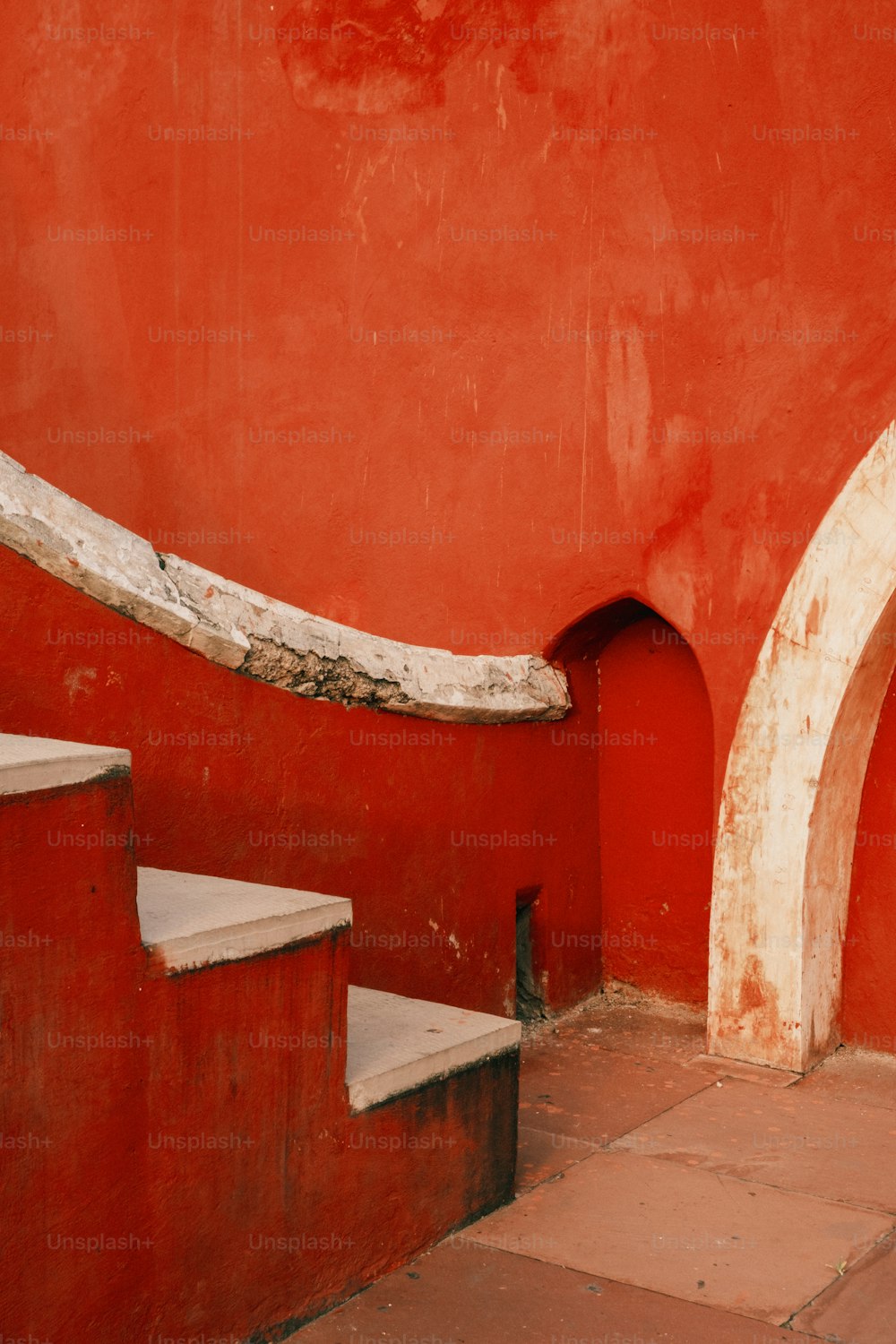 a red wall with a white arch next to it