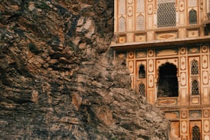 Ein Steingebäude mit geschnitzten Fenstern an der Seite eines Berges