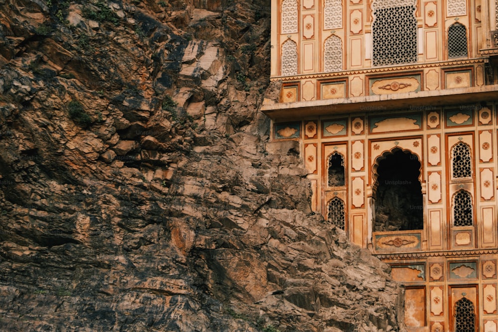 a stone building with carved windows on the side of a mountain