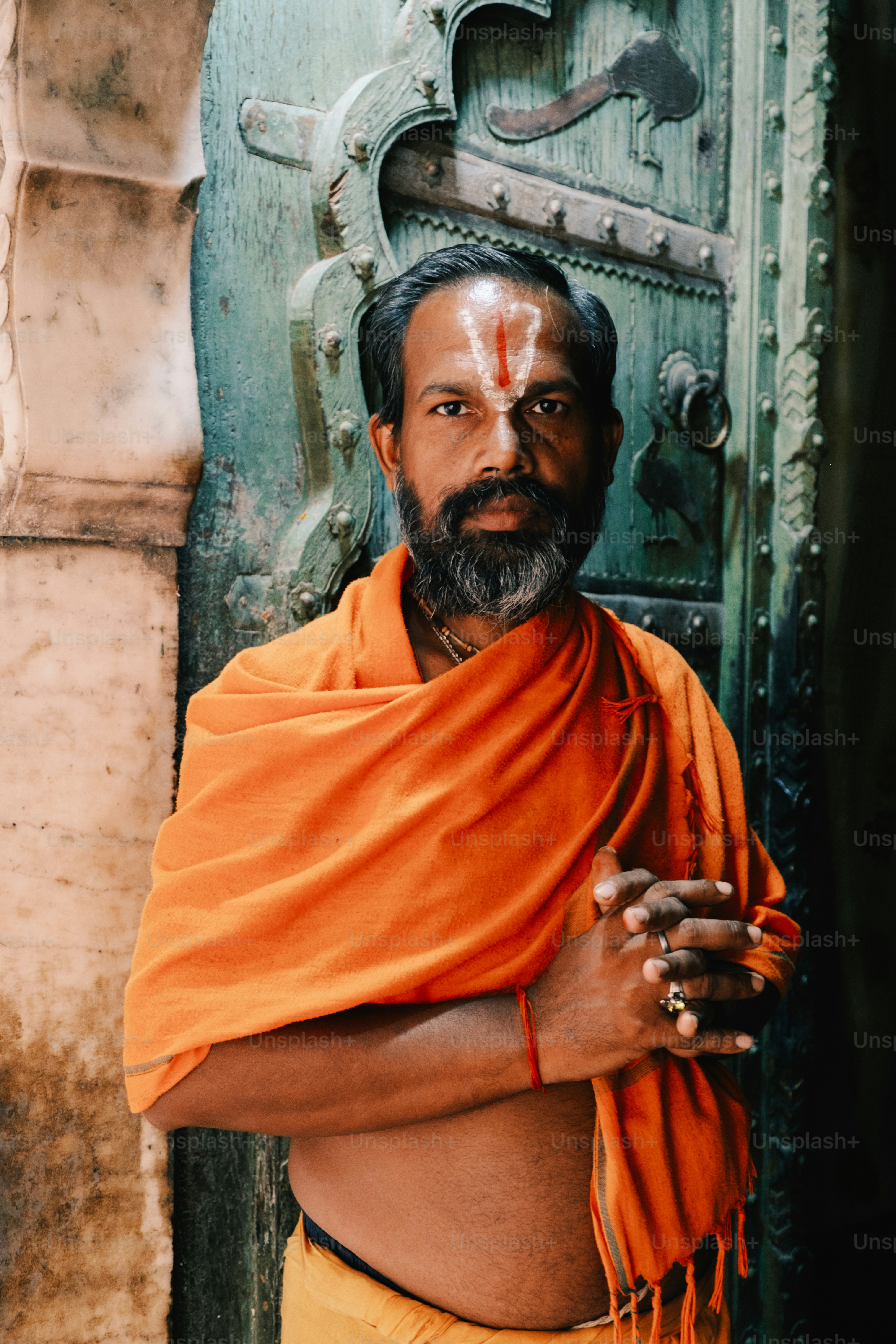 a man wearing an orange shawl standing in front of a door