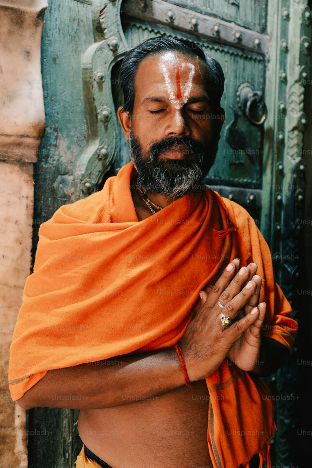 a man with his eyes closed wearing an orange cloth