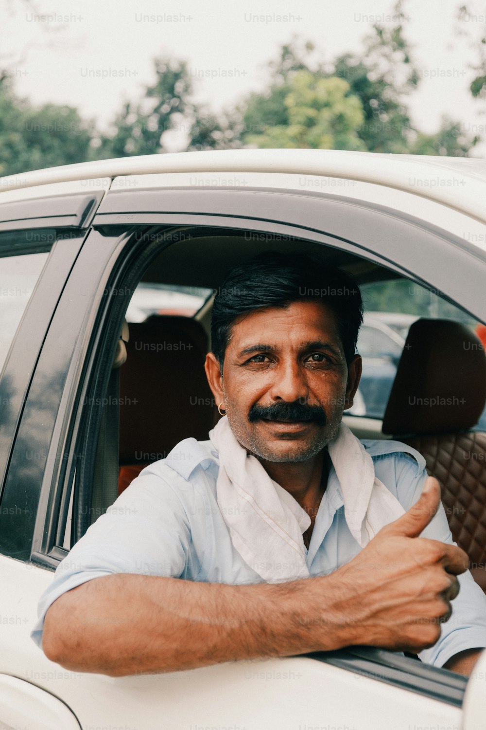 Un hombre sentado en un coche dando un pulgar hacia arriba