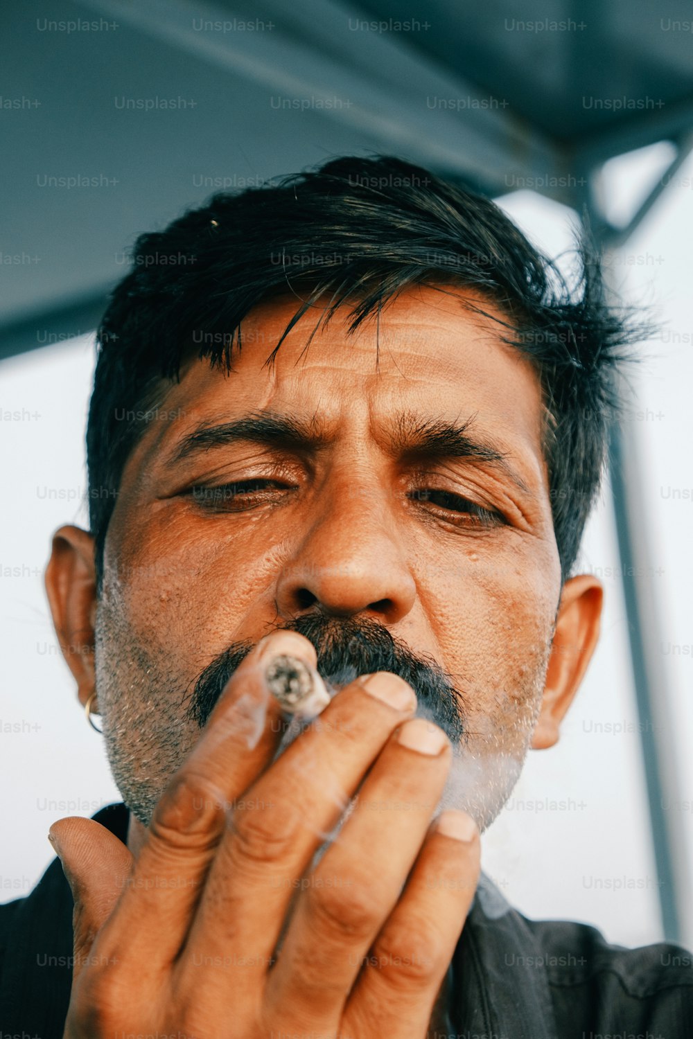 Un homme fume une cigarette à l’extérieur