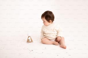ein Baby, das neben einem Spielzeug auf dem Boden sitzt