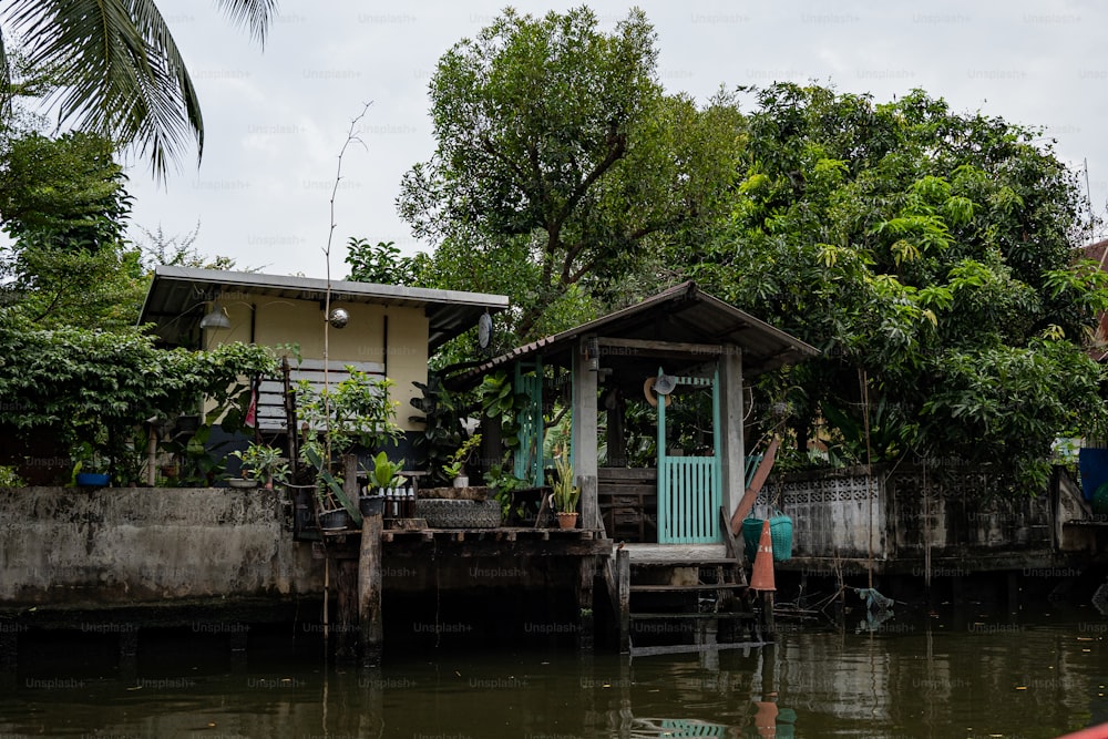 a house sitting on top of a river next to a lush green forest