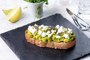 a piece of bread topped with guacamole and feta