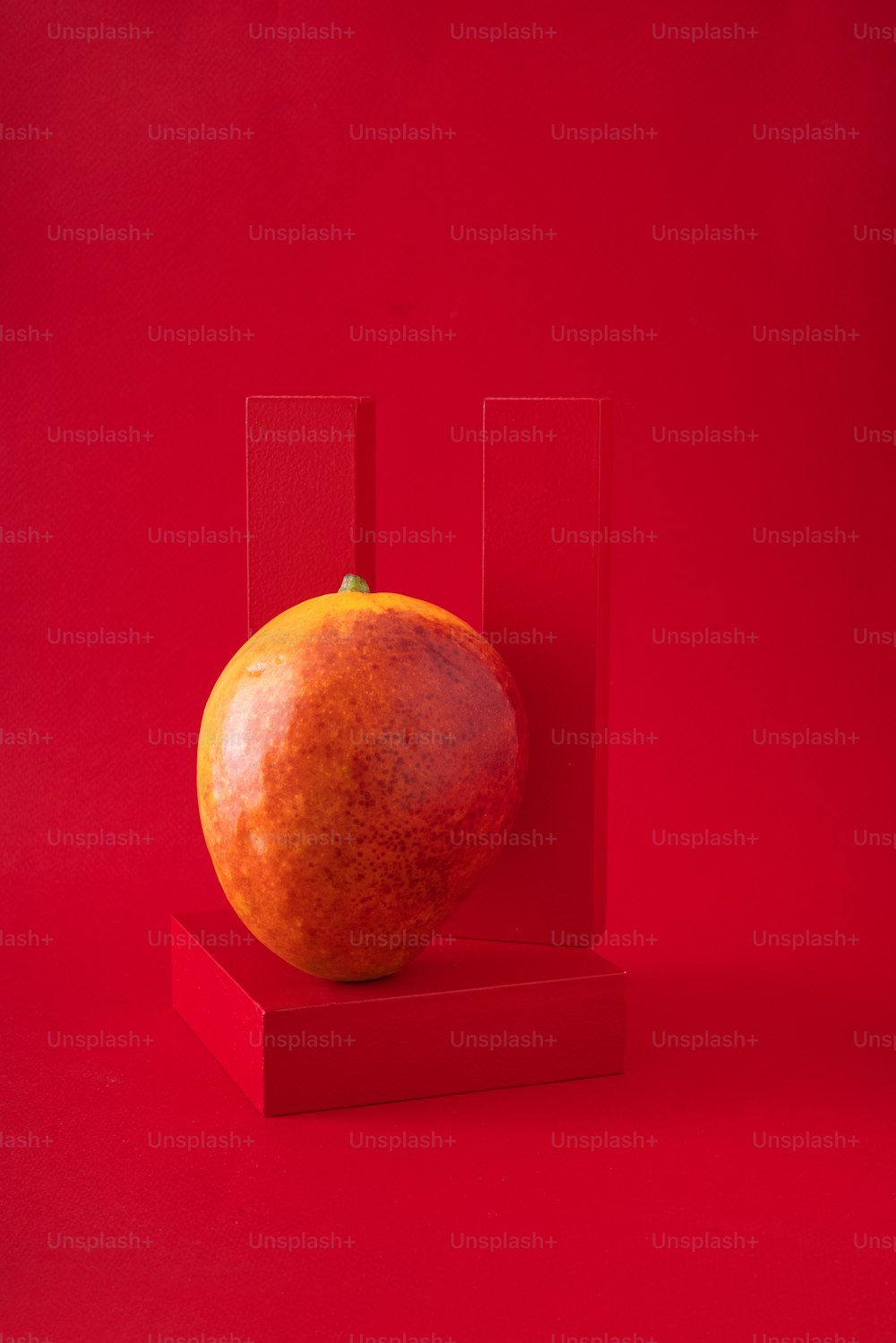 una mela seduta sopra una superficie rossa