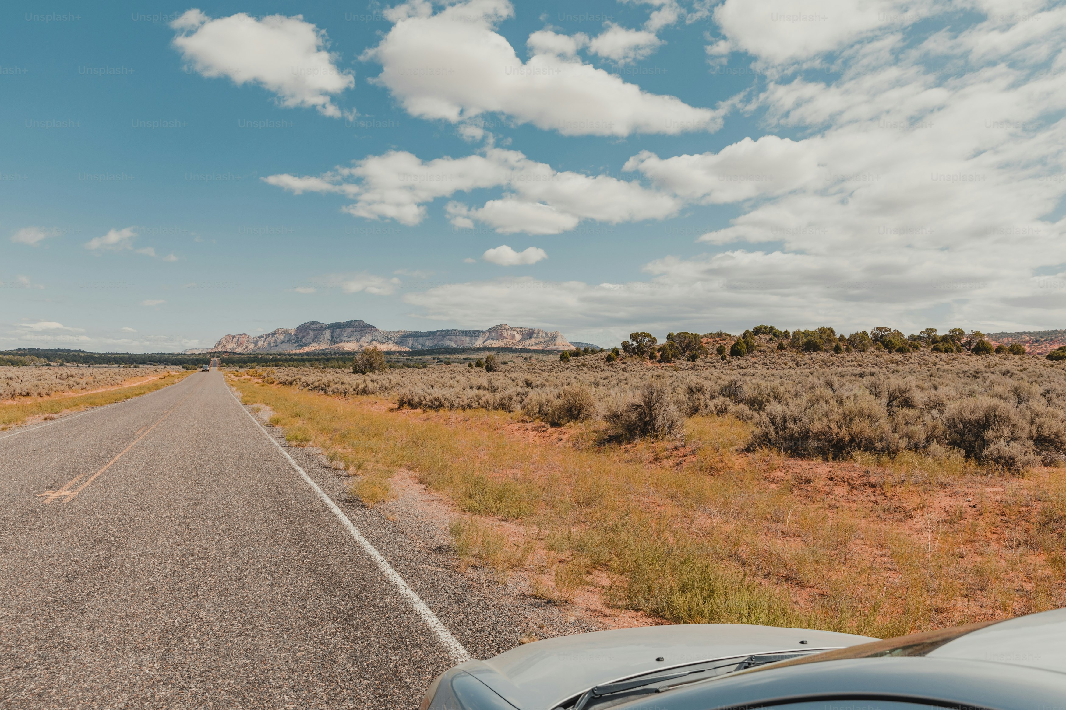 ein Auto, das mitten in der Wüste eine Straße hinunterfährt