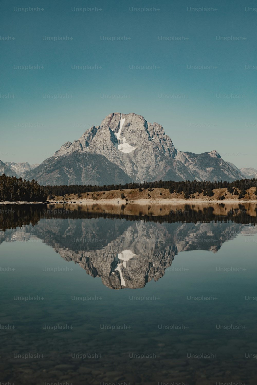 uma montanha é refletida na água parada de um lago