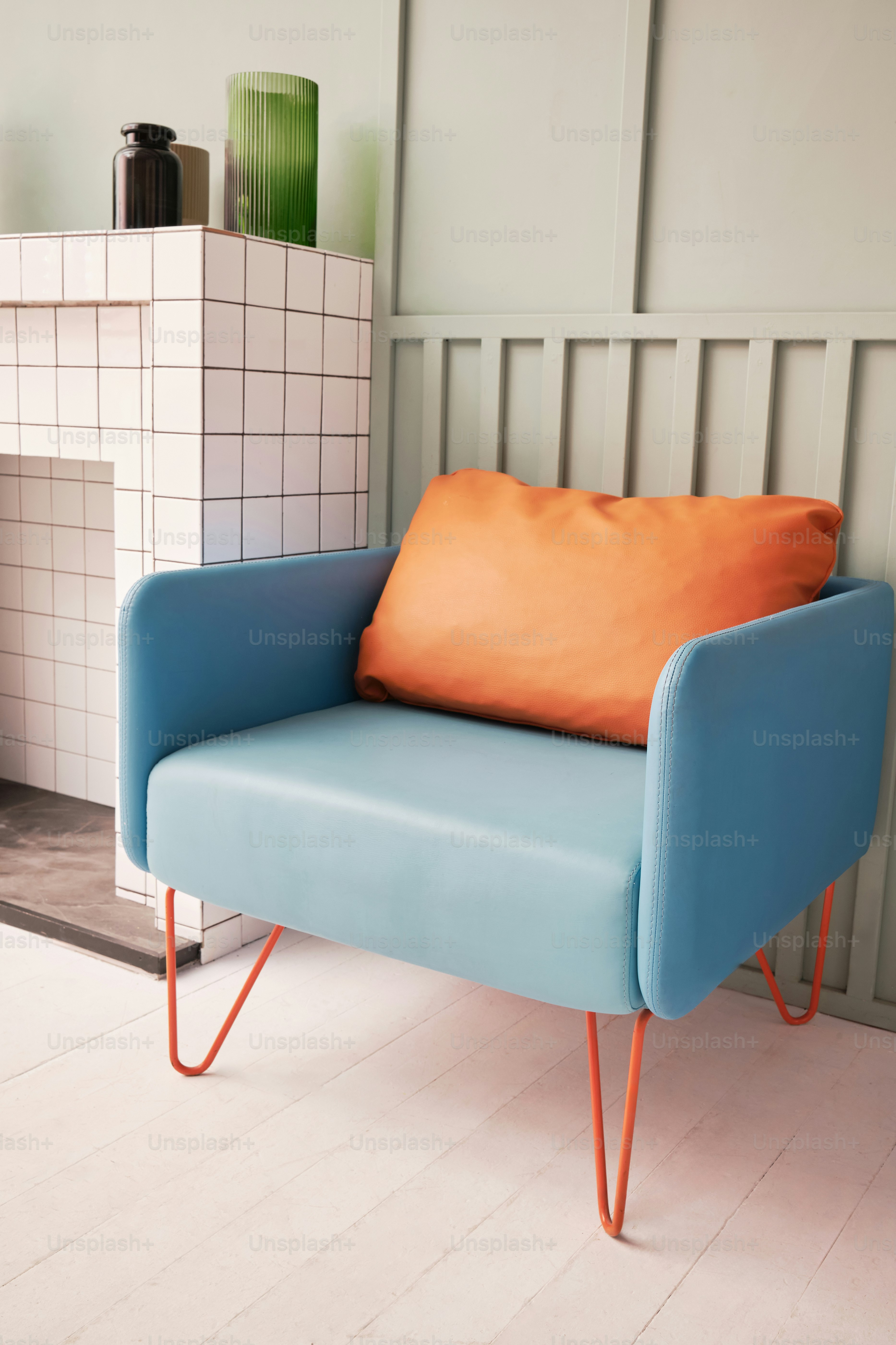 a blue chair with an orange pillow sitting in front of a fireplace