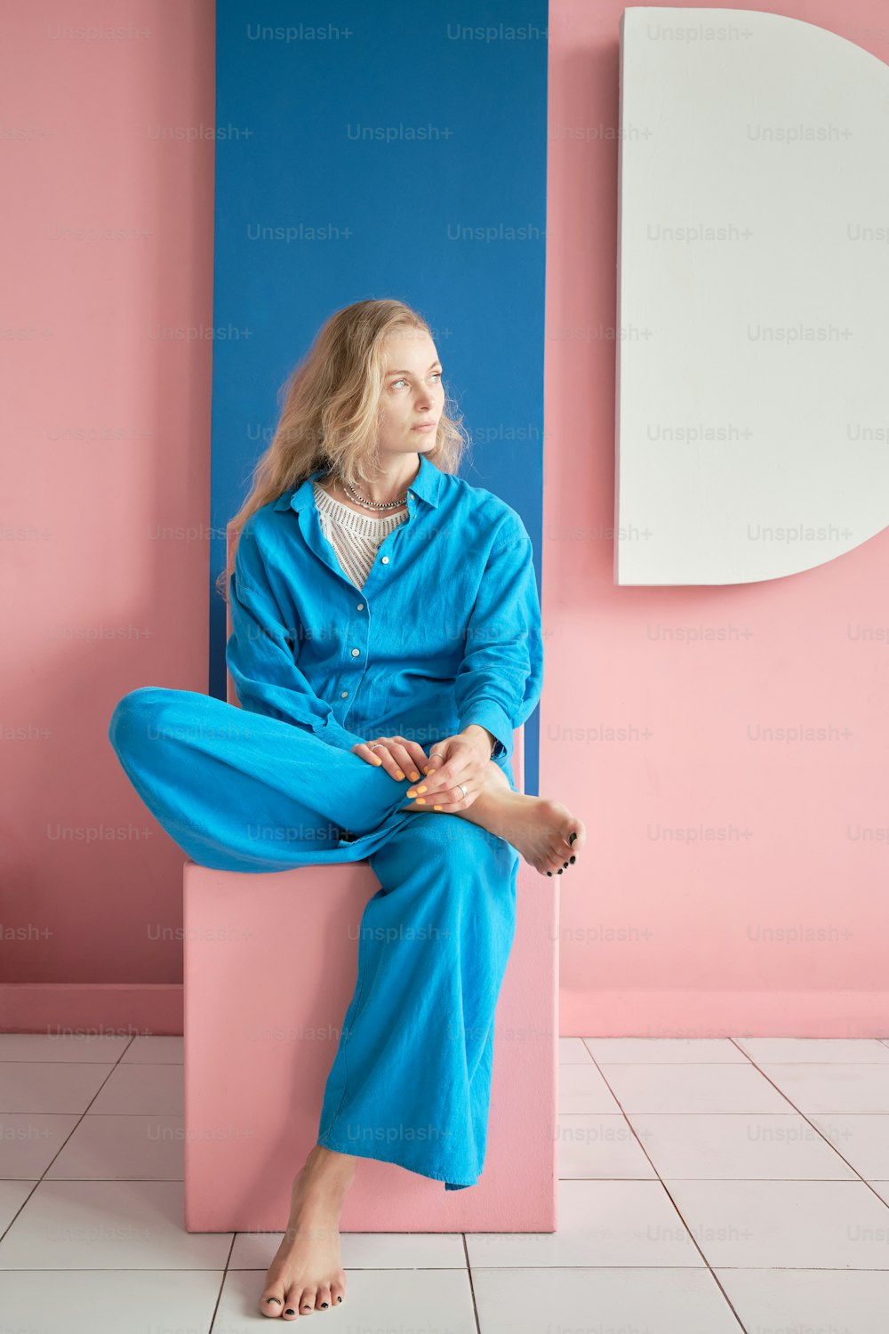 a woman sitting on a pink and blue block