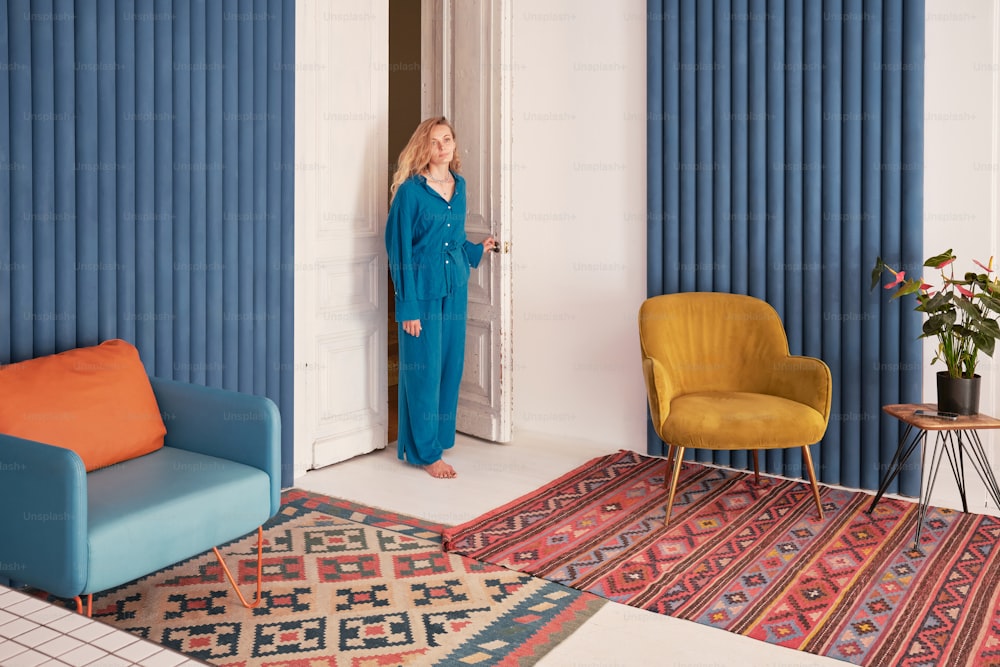 a woman in a blue jumpsuit standing in a doorway