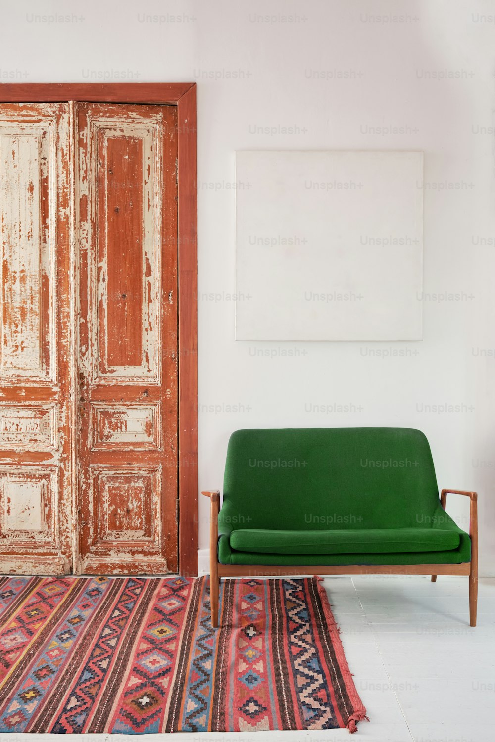 un canapé vert assis devant une porte en bois