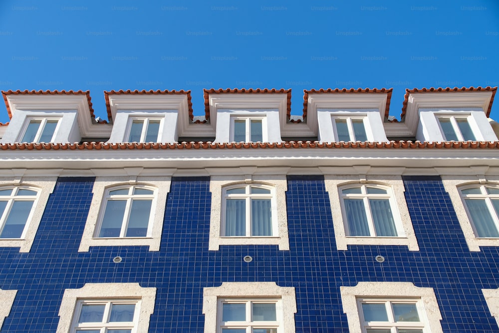 ein blau-weißes Gebäude mit Fenstern und Ziegeldach