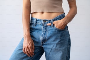 a woman wearing a tan crop top and blue jeans