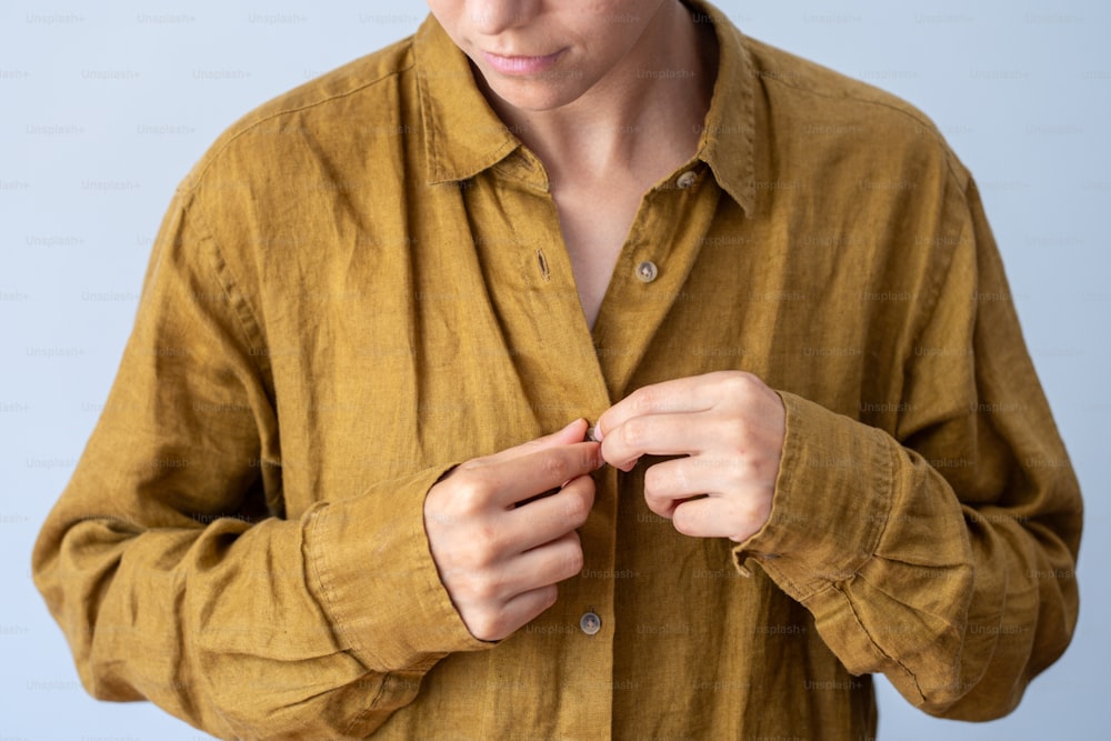 a man in a brown shirt is tying his tie