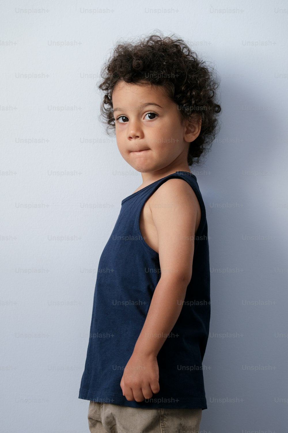 a little boy standing in front of a blue wall