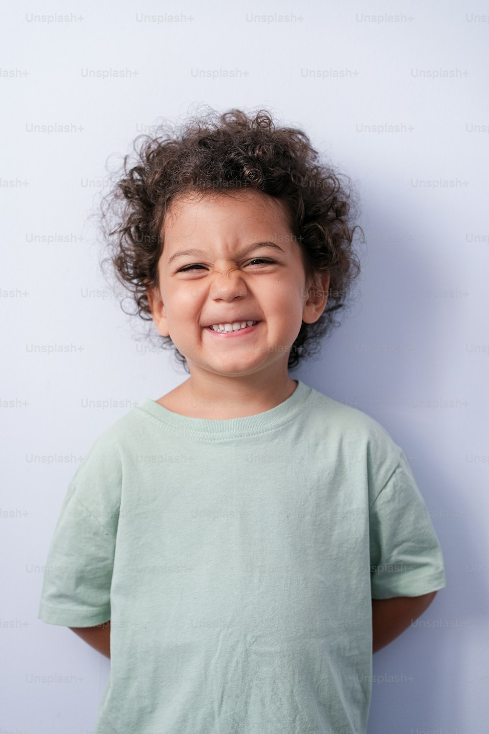 Uma criança pequena com cabelo cacheado está sorrindo