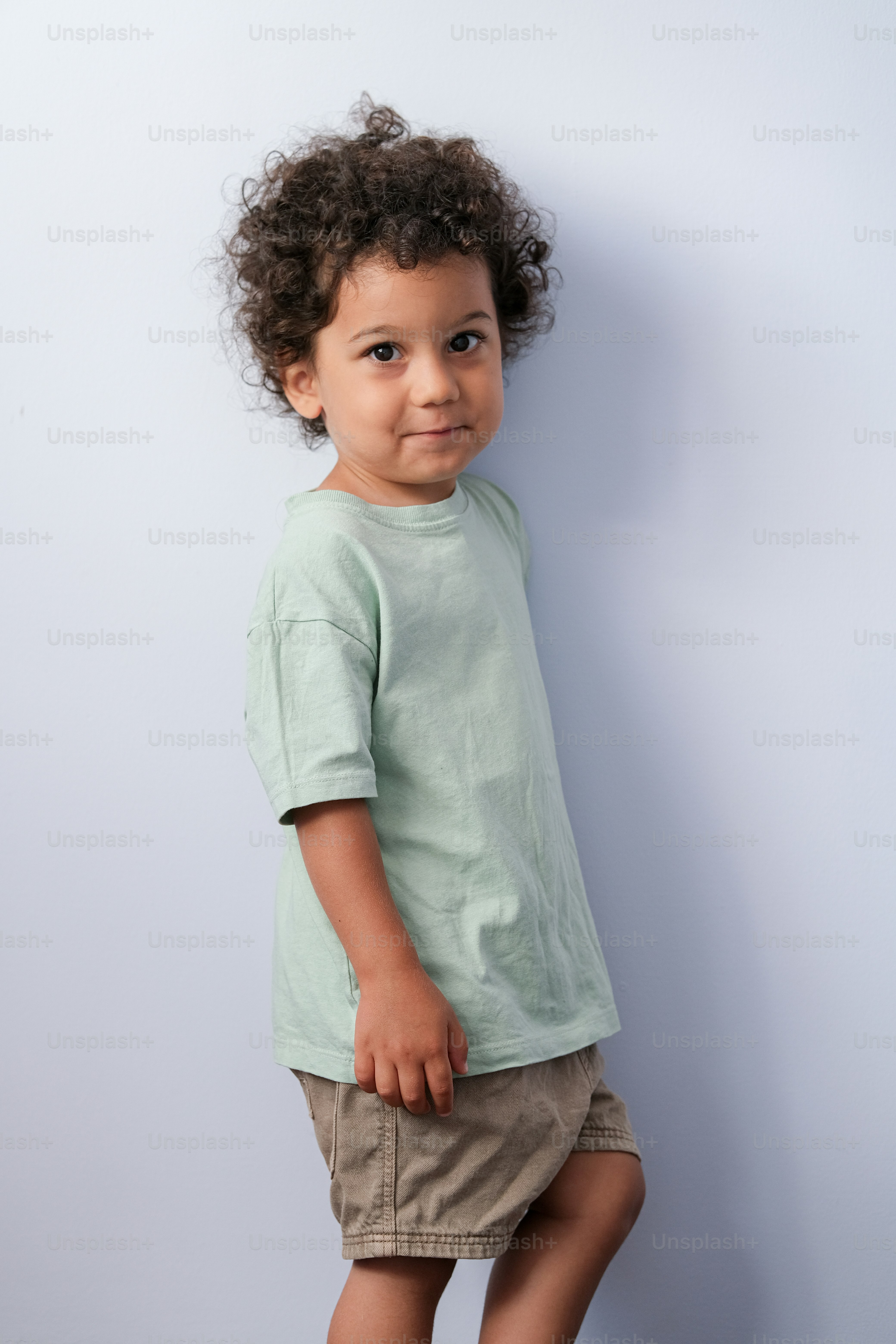 Un niño pequeño parado frente a una pared blanca foto – Imagen de Moda ...
