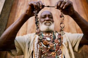 a man is holding a necklace with beads on it