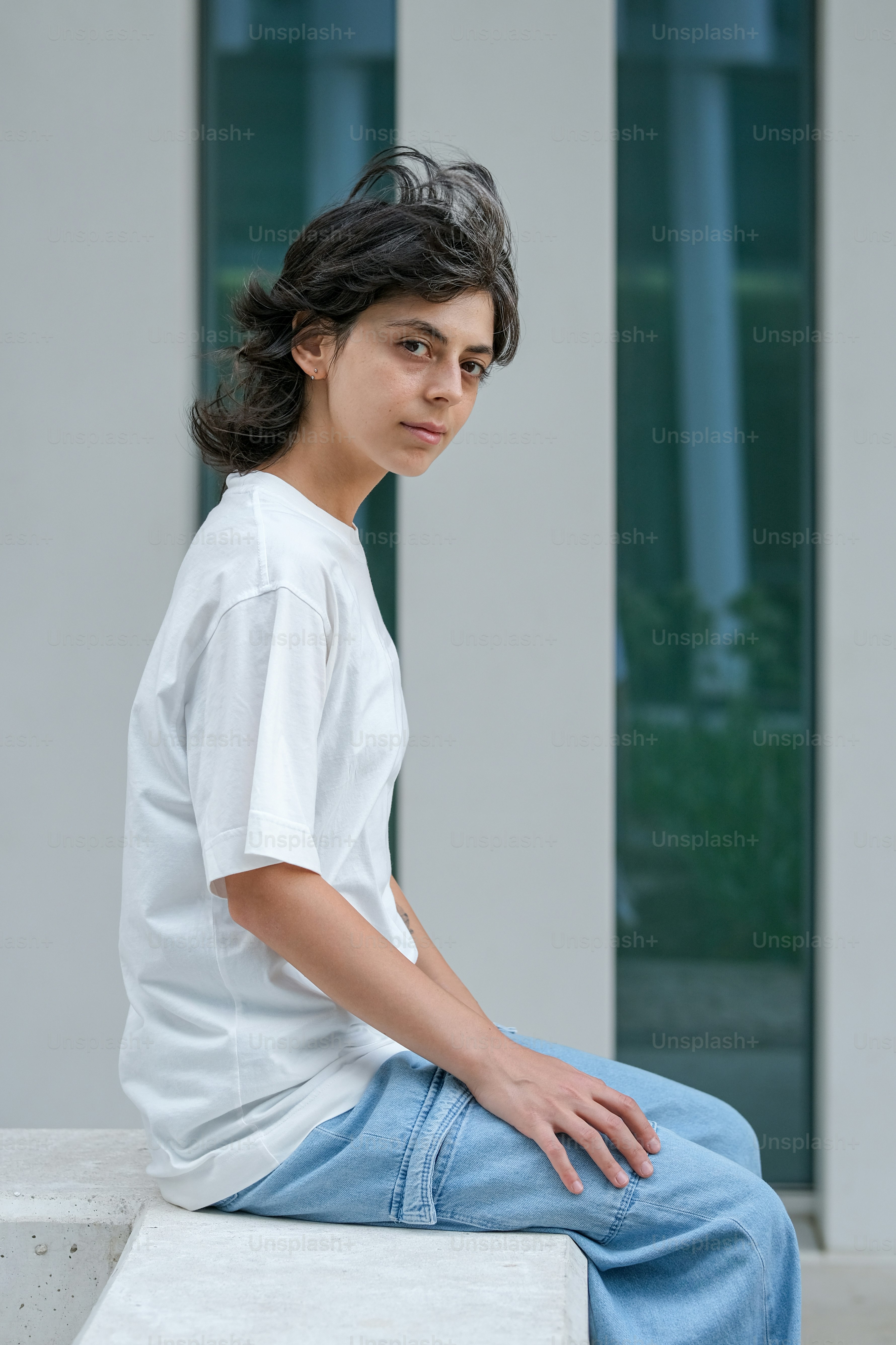 a young man sitting on a bench in front of a building