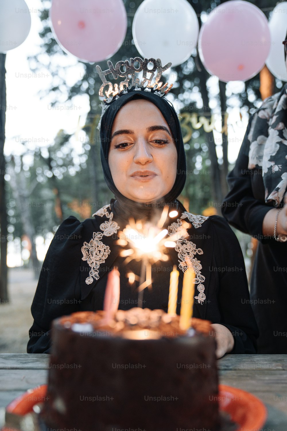 a woman wearing a tiara blowing out candles on a cake