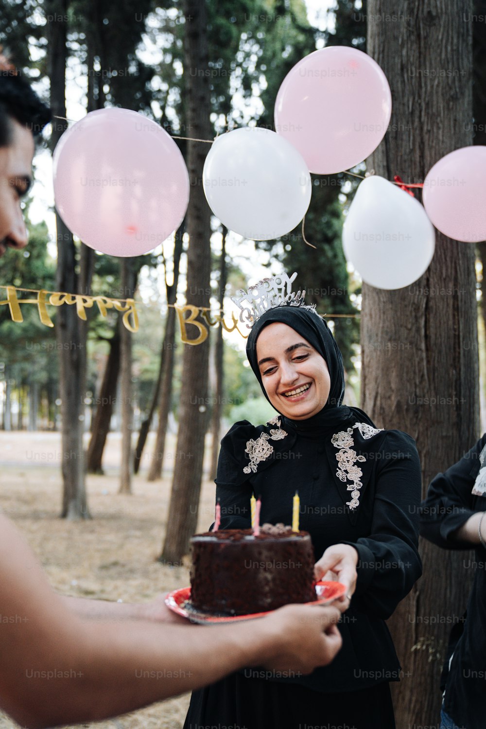 a woman in a hijab is holding a cake