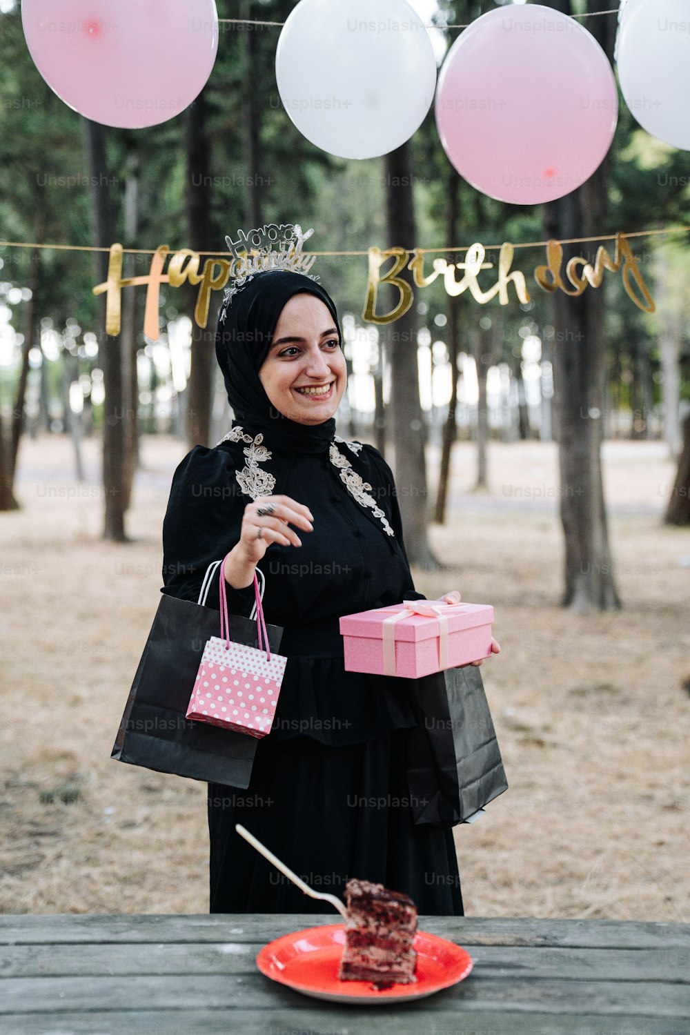 a woman in a hijab holding a pink gift box