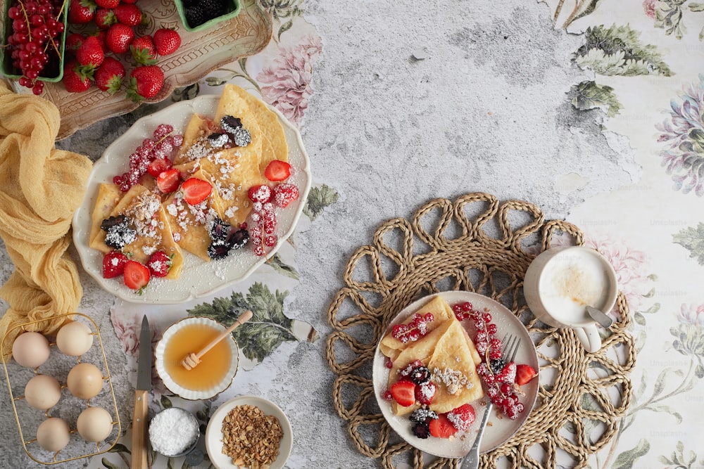 a table topped with plates of food next to a bowl of fruit